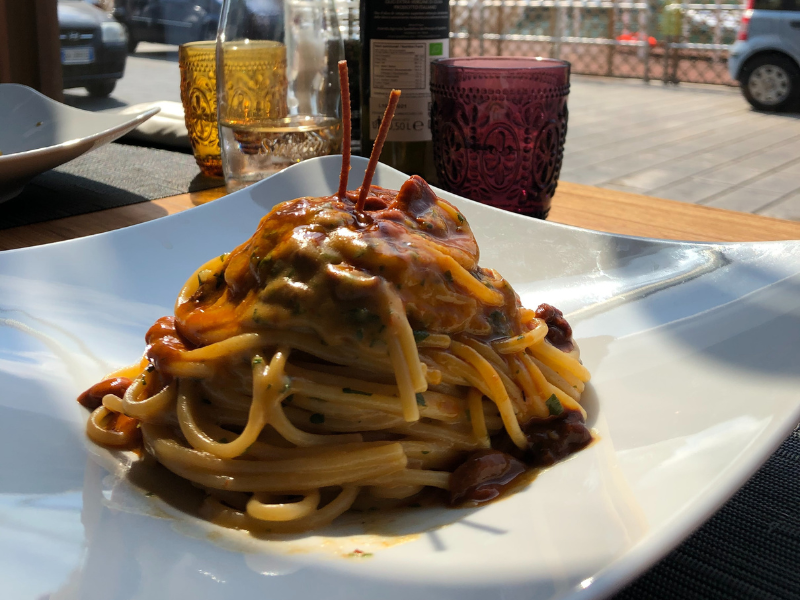 “Plate of spaghetti topped with a rich sea urchin sauce, served in an elegant setting with a rustic Sicilian backdrop.”<br />
